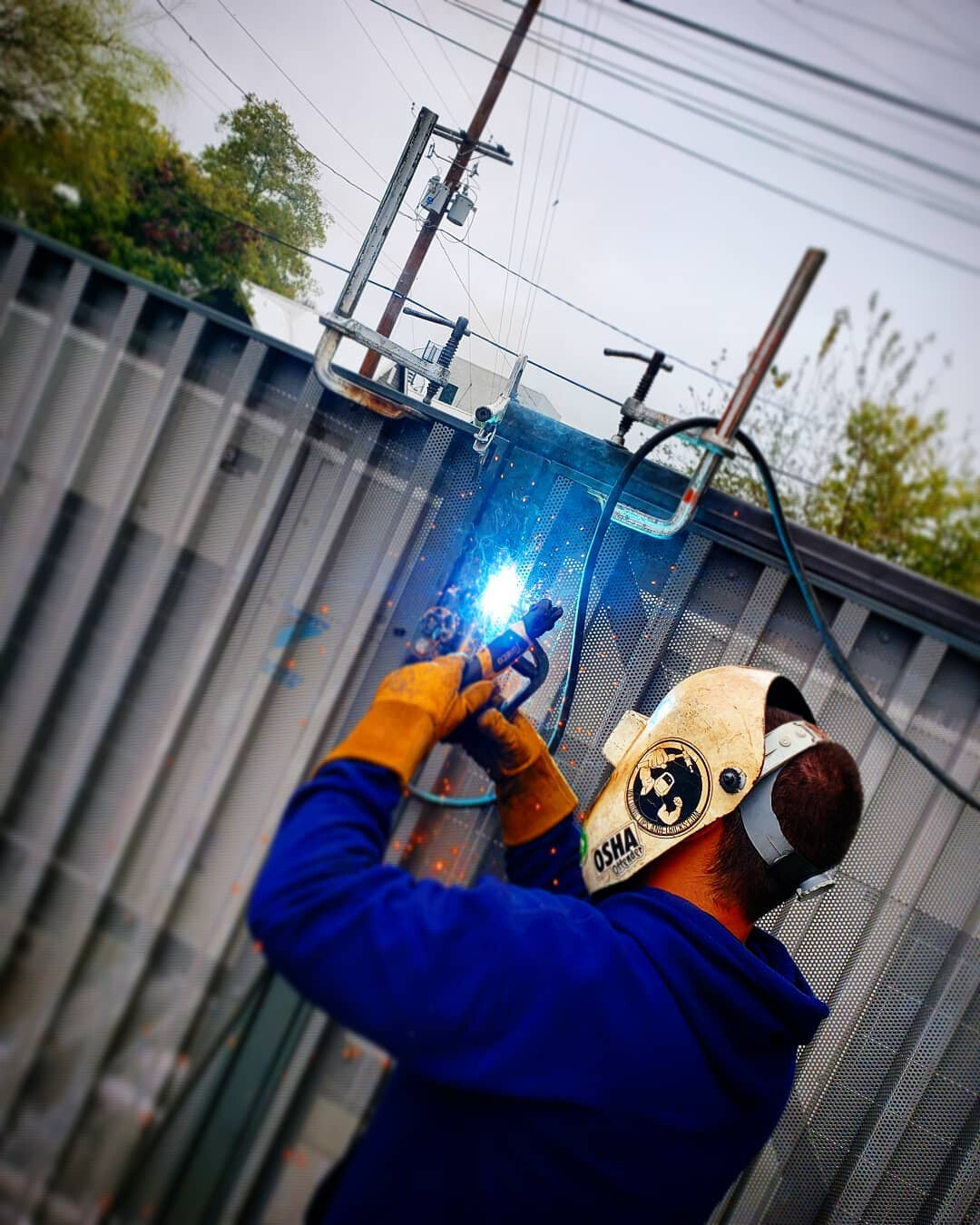 Welder stick welding a steel gate frame on site, bright arc and sparks